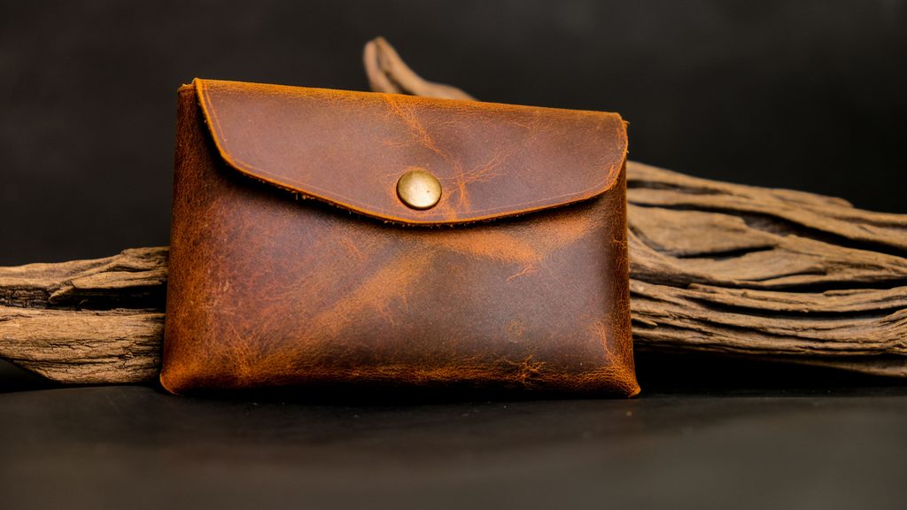Handmade brown leather wallet with brass snap button showing natural patina